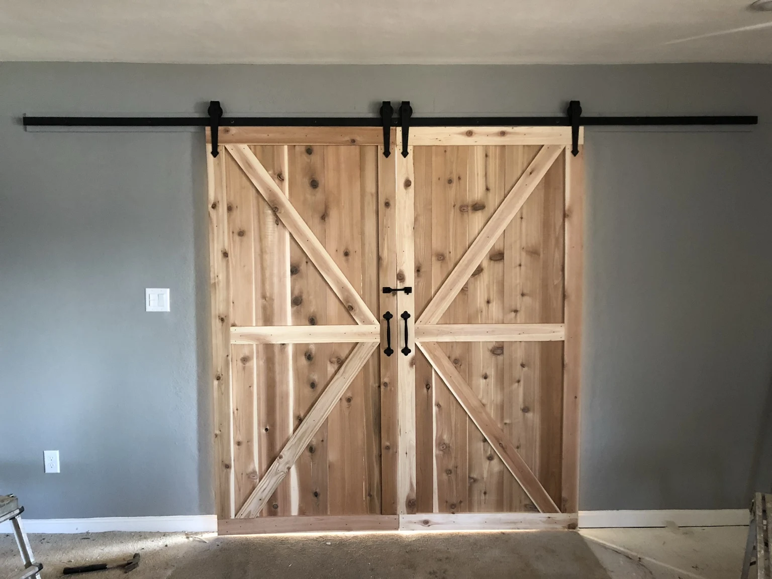 Double wood barn doors with diagonal braces and black sliding hardware