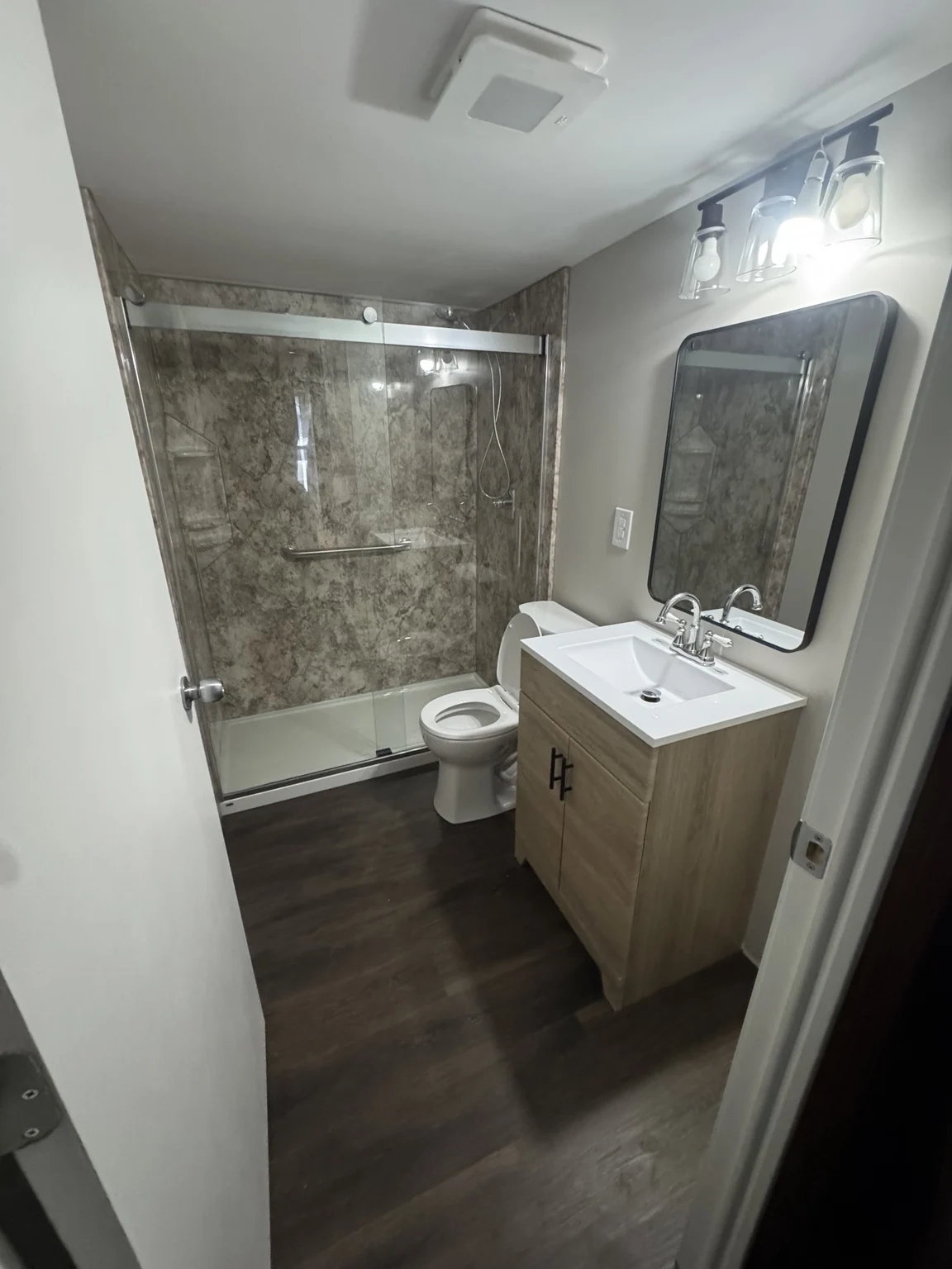 Bathroom with glass shower enclosure, wood vanity, and dark flooring