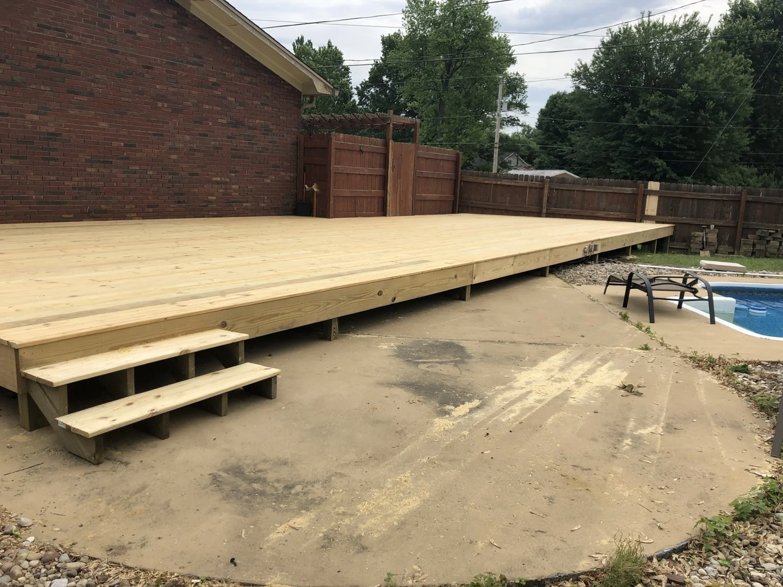 Low wood deck and two steps beside a brick house
