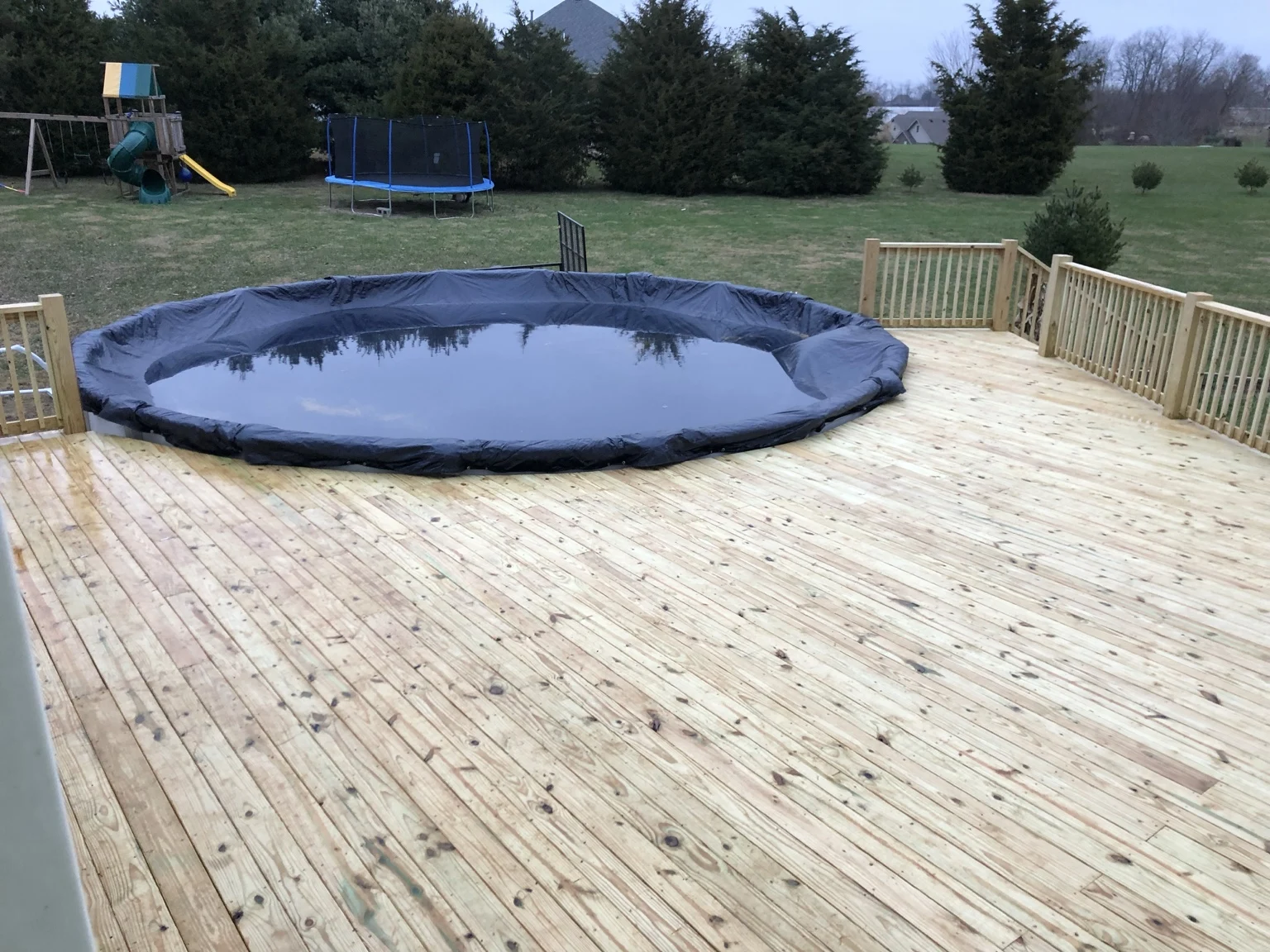 Wood deck surrounding an above-ground pool with wood railings