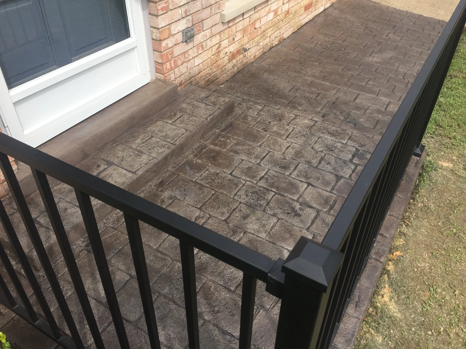 Stamped concrete porch and entry step with black metal railings