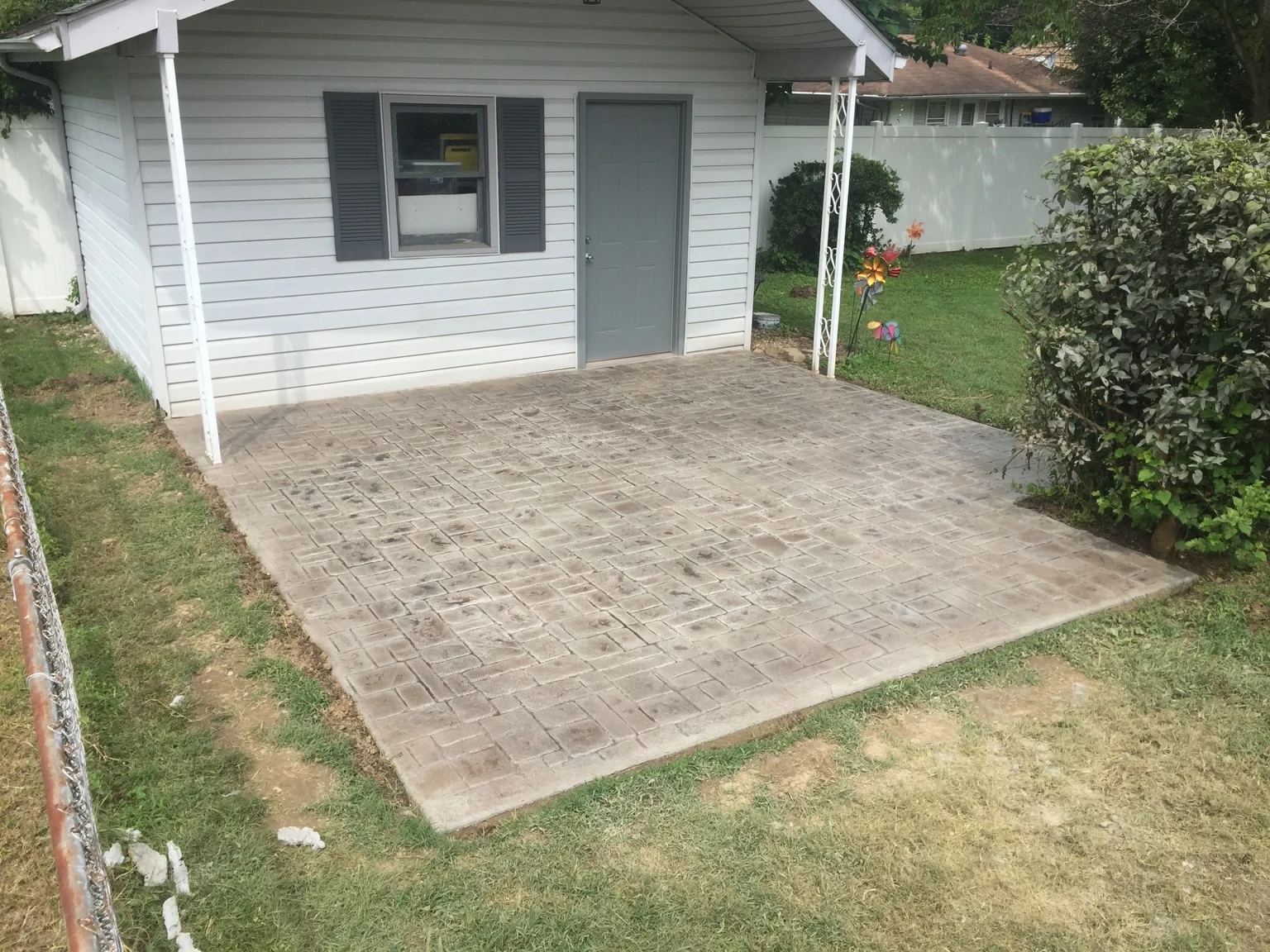 Stamped concrete patio outside a white-sided outbuilding