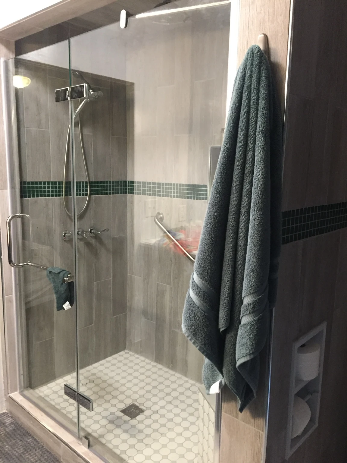 Glass shower enclosure with light wall tile and green mosaic accents