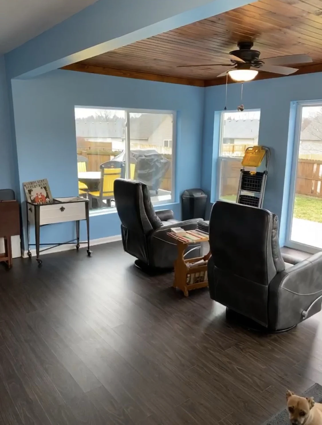 Sunroom with blue walls, dark flooring, and a natural wood ceiling